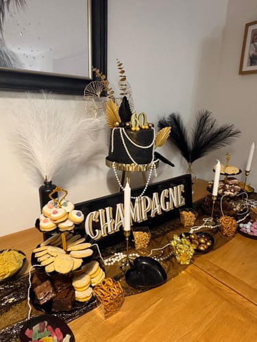 Customer's decorated party table with a cake and snacks for the 1920s Murder Mystery Game.