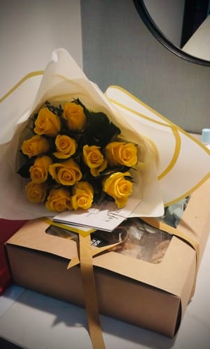 Customer's yellow Good Morning Rose Bouquet presented with a gift box of biscuits.