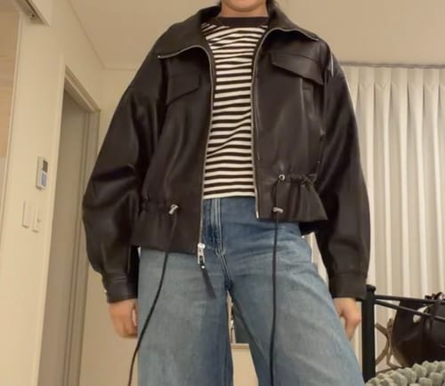 Reviewer wearing the black Faux Leather Drawstring Bomber Jacket open with the drawstrings loose.