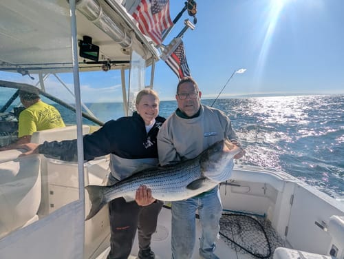 Customer's Thin Red Line Flag flying on a boat while two people hold up a large fish.