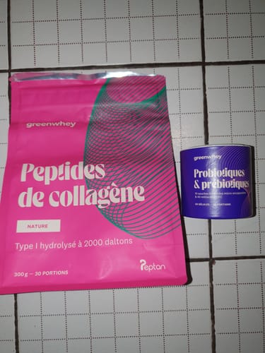 Photo d'un client montrant le sachet rose de Peptides de Collagène à côté d'un pot de probiotiques sur un sol carrelé.
