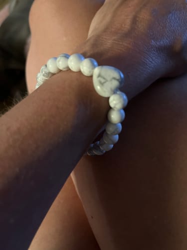 Customer wearing a white marbled crystal bracelet with a heart-shaped bead on their wrist.