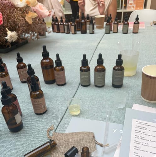 Reviewer's table at the Perfume Making Workshop, with many amber essential oil bottles and tools for blending.