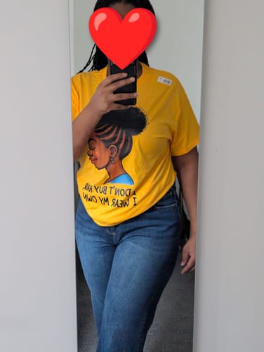 Reviewer wearing a yellow unisex t-shirt with a graphic of a woman and text reading "I DON'T BUY HAIR I WEAR MY OWN".