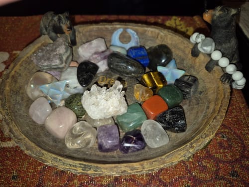 Customer's collection of colorful crystals from their subscription in a decorative wooden bowl, featuring a white quartz cluster.