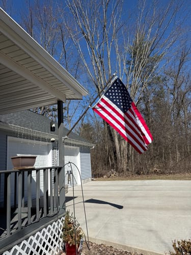 Reviewer's bronze Prestige House Flag Pole with an American flag mounted on the side of a house.