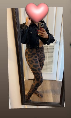 Reviewer in a mirror selfie showing the fit of the leopard-print Naked Print Tights, styled with a cropped black jacket.