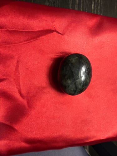 Reviewer's dark, polished oval crystal from the VIP Crystal Club resting on a red satin cloth.