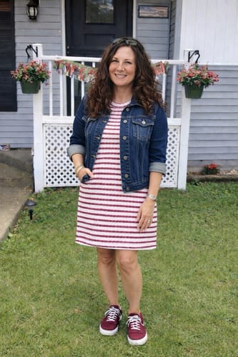 Reviewer standing outside wearing the striped tee dress, styled with a denim jacket and sneakers.