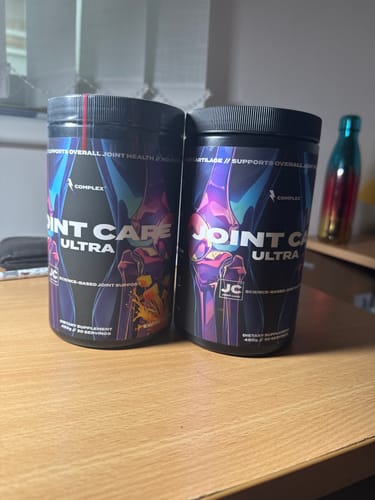 Customer's two black tubs of Joint Care Ultra sitting side-by-side on a wooden desk.