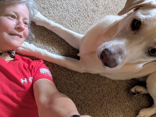 Customer lying on the floor with her dog, wearing the red 'Remember Everyone Deployed' Tee.