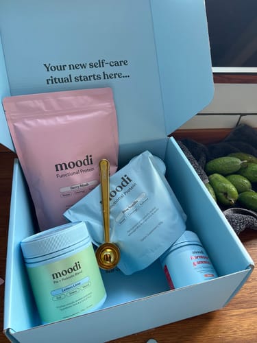 Customer's blue Moodi box filled with products, including the Lemon Lime Pre + Probiotic Blend in a green tub.
