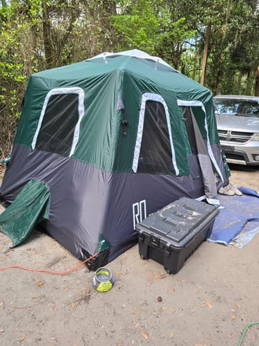 Reviewer's green and black Large-Sized 2-Step Cabin Tent set up at a wooded campsite.