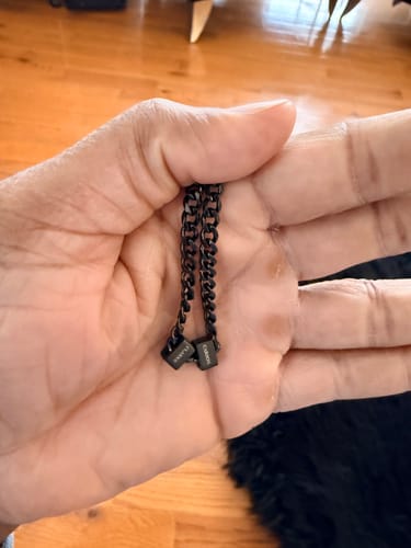 Close-up of a customer holding two black personalized pendants from the bracelet.
