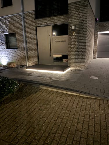 Rezensentbild des LEDVANCE LED-Streifens, der nachts mit warmweißem Licht eine Eingangsstufe beleuchtet.