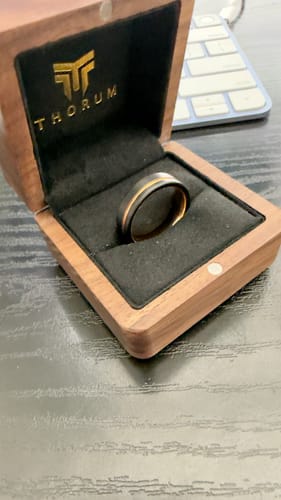Customer's The Legend ring, black with a rose gold inlay, resting in its wooden presentation box.