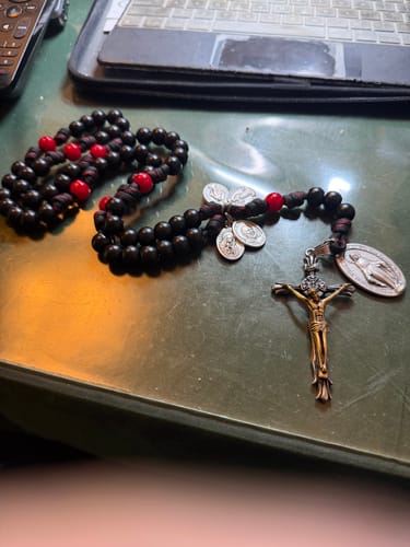 Reviewer's two-tone crucifix from the necklace, shown attached to a custom rosary with black and red beads.