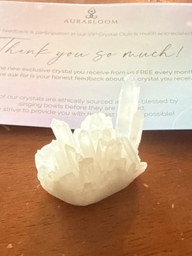 Reviewer's clear quartz crystal cluster from the VIP Crystal Club, shown on a wooden surface.