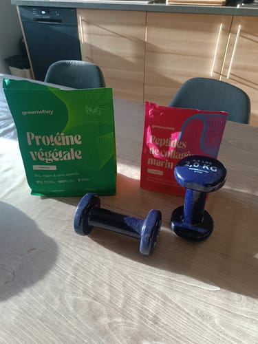 Le sachet de Protéine Végétale Biop d'un client posé sur une table à côté de deux haltères bleus.