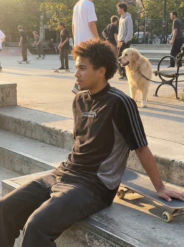 Customer wearing the black Suede Panel SUPERMADE T-Shirt with contrast panels and shoulder stripes at a skate park.
