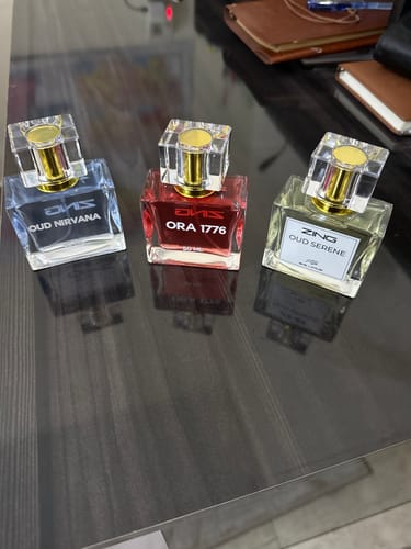 Customer's three perfume bottles from the OUD Supreme BUNDLE, showing Nirvana, Serene, and Ora 1776 on a desk.