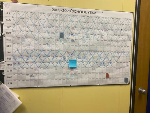 Reviewer's large School Year Calendar on an office wall, filled with colorful plans and notes.
