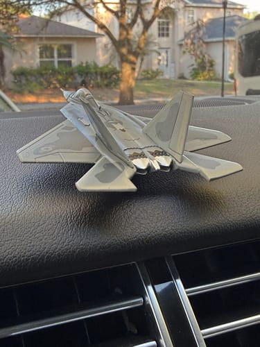 Reviewer's die-cast F-22 USAF RAPTOR® model resting on a car's black dashboard.