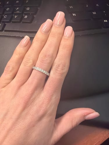 A reviewer's hand wearing the sparkling Eternity Band Ring on their finger.
