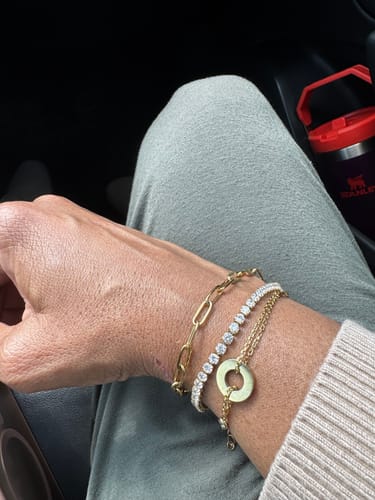 Customer's wrist showing the shimmering Tennis Bracelet stacked with two other gold-toned bracelets.