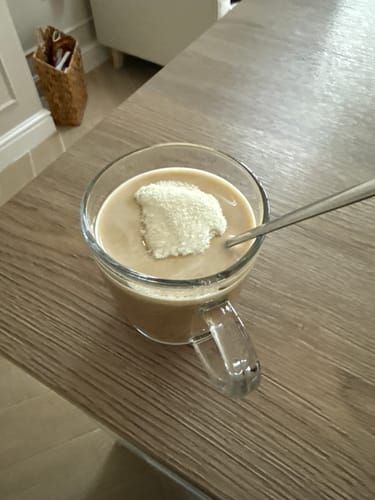 Customer adds a scoop of Halal Collagen Protein powder to a drink in a clear glass mug.