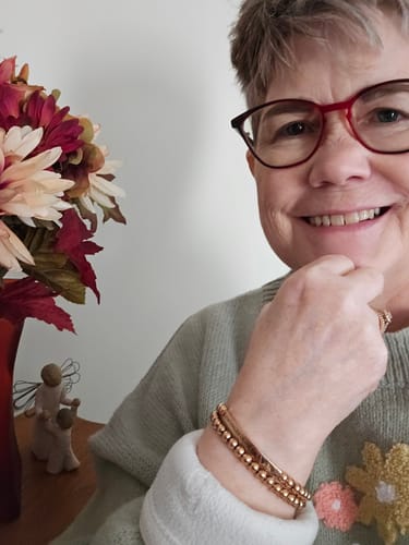 Reviewer smiling while showing the rose gold DAUGHTER OF THE KING bracelet set on her wrist.
