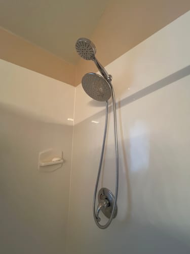 Reviewer's installed 3-Spray Dual Shower Head Set, showing the rain shower and handheld heads in a white shower stall.