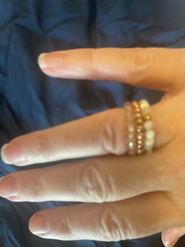 Reviewer's hand wearing a stack of three Earthstone stretch rings, including the white Mother of Pearl ring.