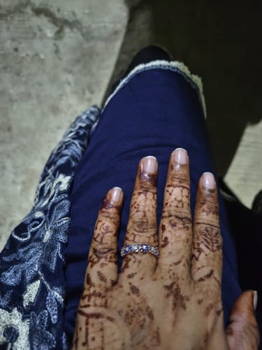 Reviewer's hand, decorated with henna, wearing the stone-studded Glinting Crown Ring on their finger.