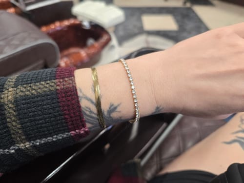 Customer's wrist wearing the shimmering Tennis Bracelet stacked with another gold bracelet.