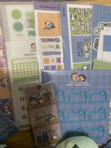 Partial view of a customer's Staying Cozy Hobonichi Cousin Monthly Kit among several other book-themed sticker sheets.