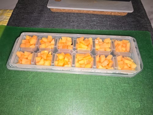Rezensent zeigt gewürfelte Bio-Papaya in einer Eiswürfelform, bereit zum Einfrieren für Smoothies.
