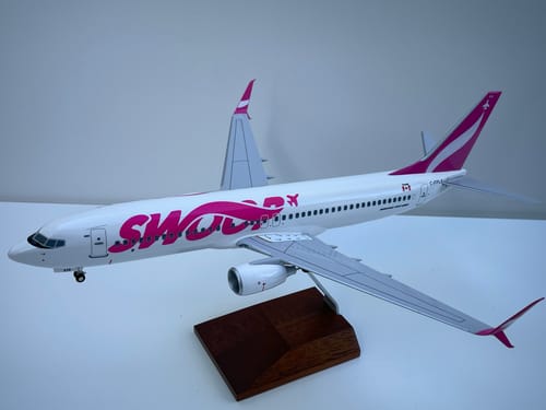 Customer's assembled SKYMARKS SWOOP 737-800 model plane with magenta livery displayed on its wooden stand.