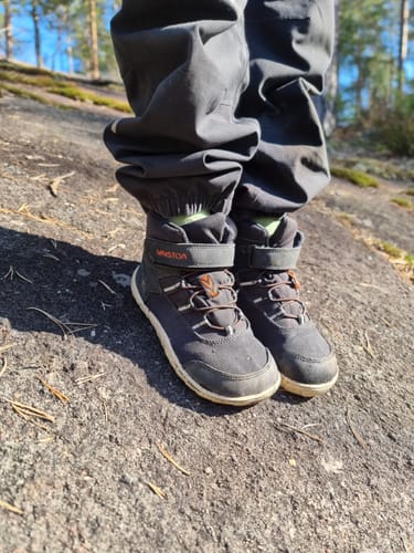 Asiakkaan Vaistoa Kaste -kengät lapsen jalassa ulkona kalliolla.