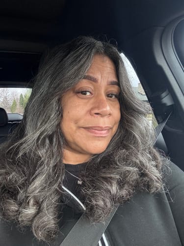 Reviewer smiles in a car, showing the natural, wispy look of her Aliva lashes.
