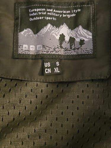Close-up of the size tag inside the reviewer's hiking jacket, showing 'US S' and 'CN XL'.