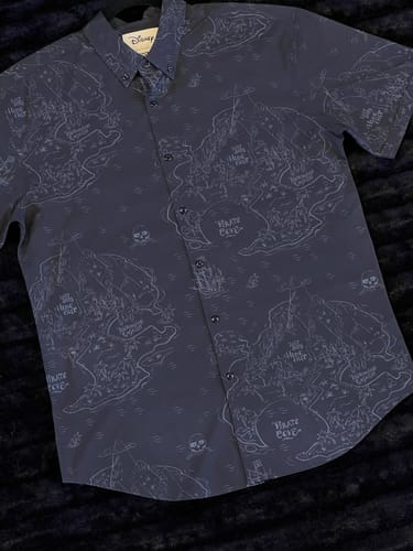 Reviewer's dark "Navigating Neverland" shirt laid flat, showing the detailed Neverland map print.