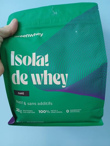 Un client tient le sachet vert d'Isolat de Whey Native, saveur café, dans sa main.