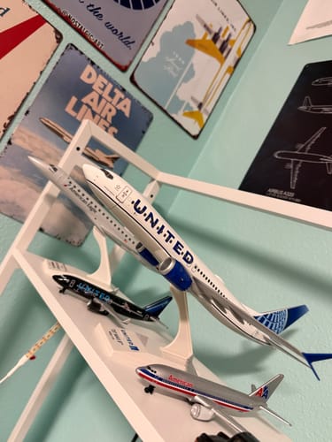 Customer's SKYMARKS UNITED 737MAX8 model airplane displayed on a white shelf among a collection of other planes.