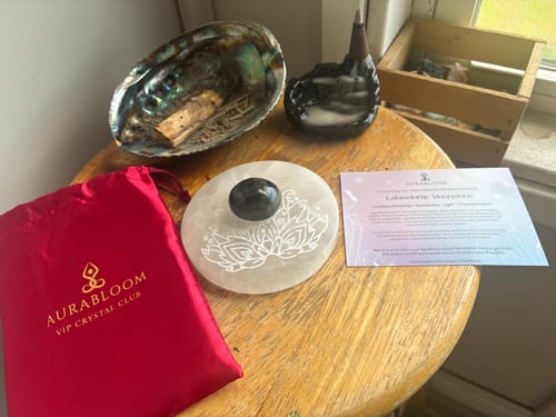 Reviewer's VIP Crystal Club items: a round Labradorite Moonstone, red bag, and information card on a wooden surface.