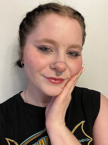 Customer smiling while wearing the BAT SEPTUM jewelry, which is connected to a thin nose chain.