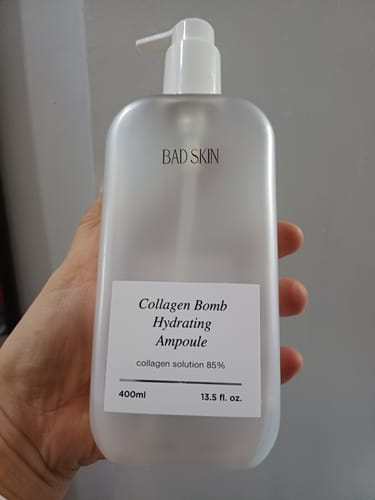 Reviewer holding the large 400ml bottle of Bad Skin Collagen Bomb Hydrating Ampoule.