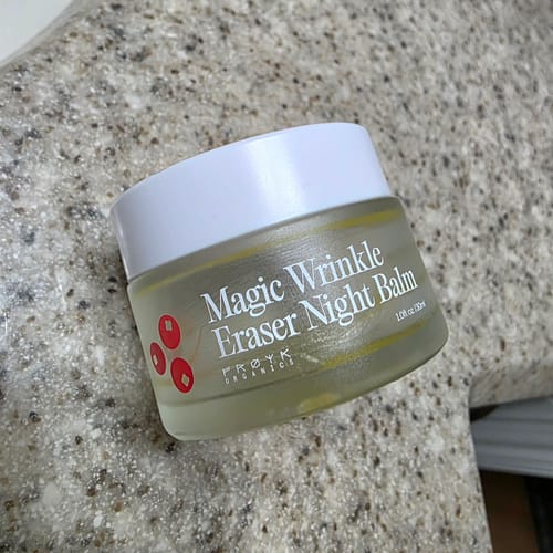Customer's frosted glass jar of Magic Wrinkle Eraser Night Balm with a white lid, sitting on a stone countertop.