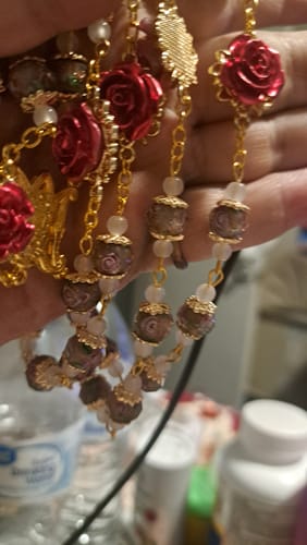 Reviewer's close-up of the large Rose Accent Devotion Rosary, showing its detailed red rose and patterned glass beads on a gold chain.