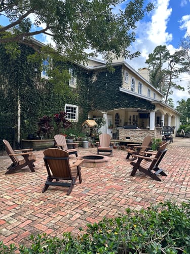 Customer's set of six brown Folding Adirondack Chairs arranged on a large brick patio.